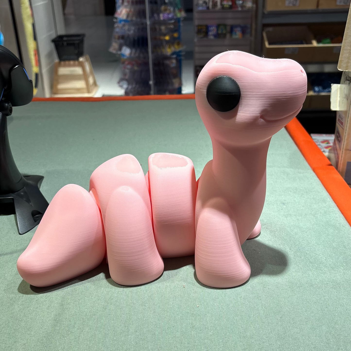 Pink toy dinosaur on a green surface with a store setting in the background